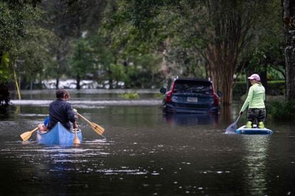 People use canoes and paddle boards to navigate a street in Orlando, Florida flooded by Hurricane Ian.