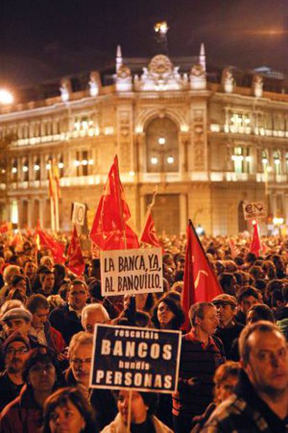 Protesters in Madrid carry placards asking why their money is being used to bail out banks.