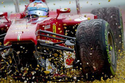 The damaged Ferrari of Fernando Alonso comes grinding to a halt in a gravel trap.