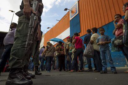 People stand in line outside a supermarket in Venezuela.