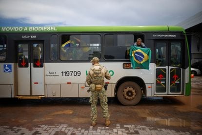 Un partidario de Jair Bolsonaro sostiene una bandera al llegar en autobús a la Academia Nacional de la Policía Federal en Brasilia
