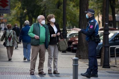 A local police officer informs a couple about the coronavirus restrictions in Madrid.