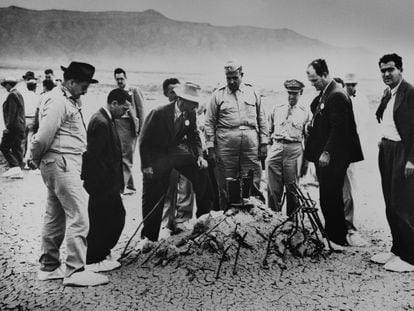 Robert Oppenheimer (wearing hat and suit), General Leslie Groves and other scientists and military personnel examine the ruins of a tower leveled by the first atomic bomb test in New Mexico.