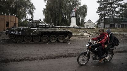 A motorcycle rider crosses a damaged tank in Izium.