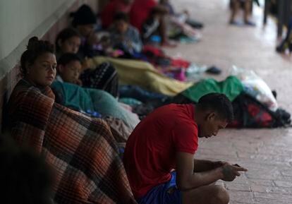 Venezuelan migrants sit along a building wall as they take cover from the rain, near the banks of the Rio Grande in Matamoros, Mexico, Saturday, May 13, 2023.