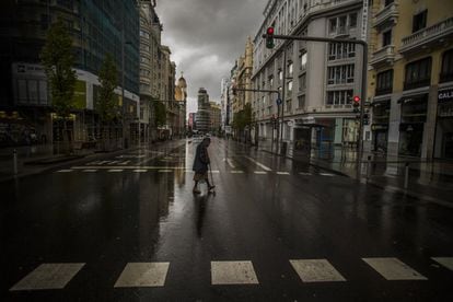A woman crosses a deserted Gran Vía in Madrid, on March 23, 2020 during the state of alarm in Spain.