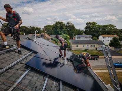 Employees of NY State Solar, a residential and commercial photovoltaic systems company, install solar panels on a roof, in August 2022, in Massapequa, New York.