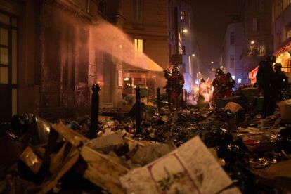 Firefighters water a facade after extinguishing a fire of rubbish during a demonstration in Paris