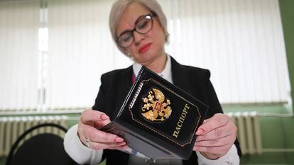 An election commission official inspects the passport of a person who came to vote at a polling station, during a presidential election in Makiivka, Russian-controlled Donetsk region, Ukraine, March 15, 2024.
