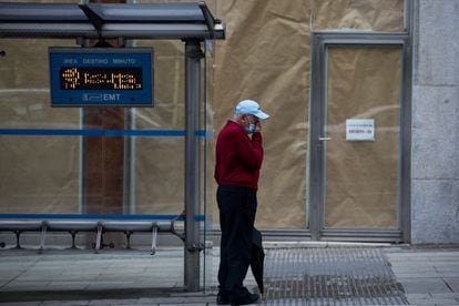 A man waits at a bus stop on Gran Vía avenue in Madrid.