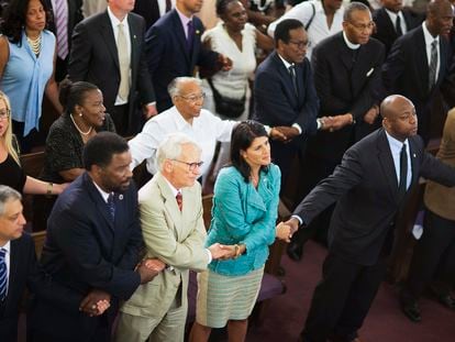 Then-South Carolina Gov. Nikki Haley, center right, joins hands with Sen. Tim Scott, right, at a memorial service at Morris Brown AME Church in Charleston, S.C., on June 18, 2015.