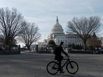 A bicyclist rides past the US Capitol building, surrounded by temporary anti-riot fencing installed around its perimeter, on the day of US President Joe Biden's State of the Union address.