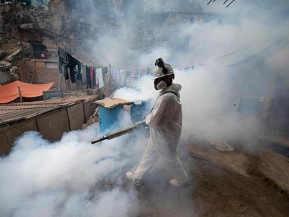 Un integrante de una brigada de salud fumiga una calle para evitar la propagación del dengue en el distrito de San Juan de Lurigancho, en Lima