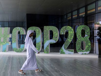 A person walks past a '#COP28' sign in Abu Dhabi, United Arab Emirates, October 1, 2023.