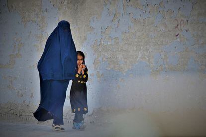 A woman in a burqa and a girl walk through Kabul in May 2022.
