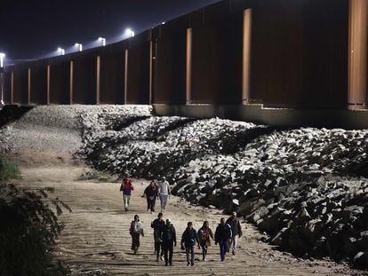 Migrants seeking asylum in the U.S. walk along the border fence on their way to be processed by Border Patrol agents after crossing into Arizona from Mexico on May 11, 2023.
