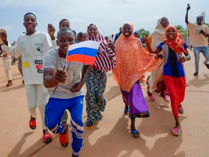 Supporters of Niger's ruling junta hold a Russian flag in Niamey, Niger, Sunday, Aug. 6, 2023.