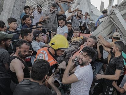 Palestinians recover a survivor among the rubble of a residential building leveled in an airstrike, in the Khan Younis refugee camp in the southern Gaza Strip, October 21, 2023.