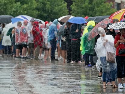 People wait in the rain ahead of a rally for President Donald Trump, Friday, July 7, 2023, in Council Bluffs, Iowa.