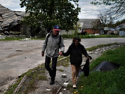 A couple walk past a bombed-out house in Kupiansk.