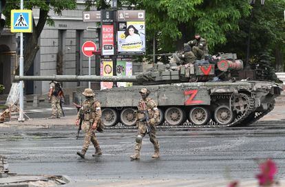 Two Wagner members walk past a mercenary company tank in the city of Rostov on Saturday.