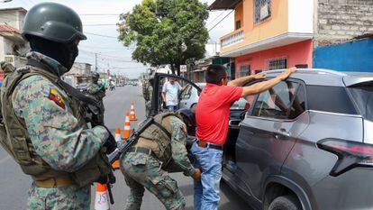 A soldier pats down a driver at a road block in Guayaquil, Ecuador, Thursday, Aug. 10, after President Guillermo Lasso declared a state of emergency.