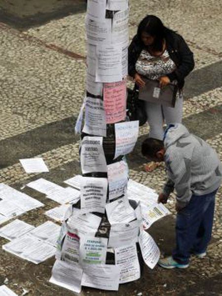 Two people read job postings on a street in São Paulo, Brazil.