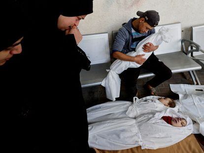 A Palestinian family stands over the bodies of their twin daughters and their son at a hospital in Rafah on December 12. The children were killed by an Israeli air strike in the southern Gaza Strip.