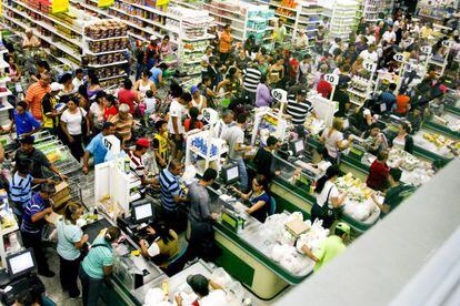 A group of people wait to purchase goods at a supermarket in San Cristóbal.