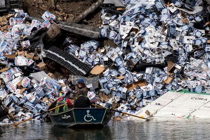 A group of fishermen claim a bottle of beer from a derailed railcar on the banks of the Clark Fork River near Quinn's Hot Springs, in St. Regis, Mont., Sunday, April 2, 2023