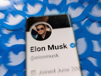 Elon Musk's profile on Twitter, displayed on a mobile phone over logos of the social network.