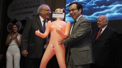 Economy Minister Luis Felipe Céspedes (r) accepts the inflatable doll.