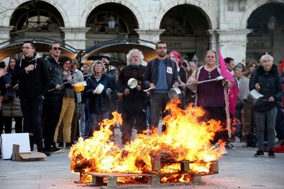 People bang pots and pans behind burning palettes while French President Emmanuel Macron seeks to diffuse tensions in a televised address to the nation, Monday, April 17, 2023
