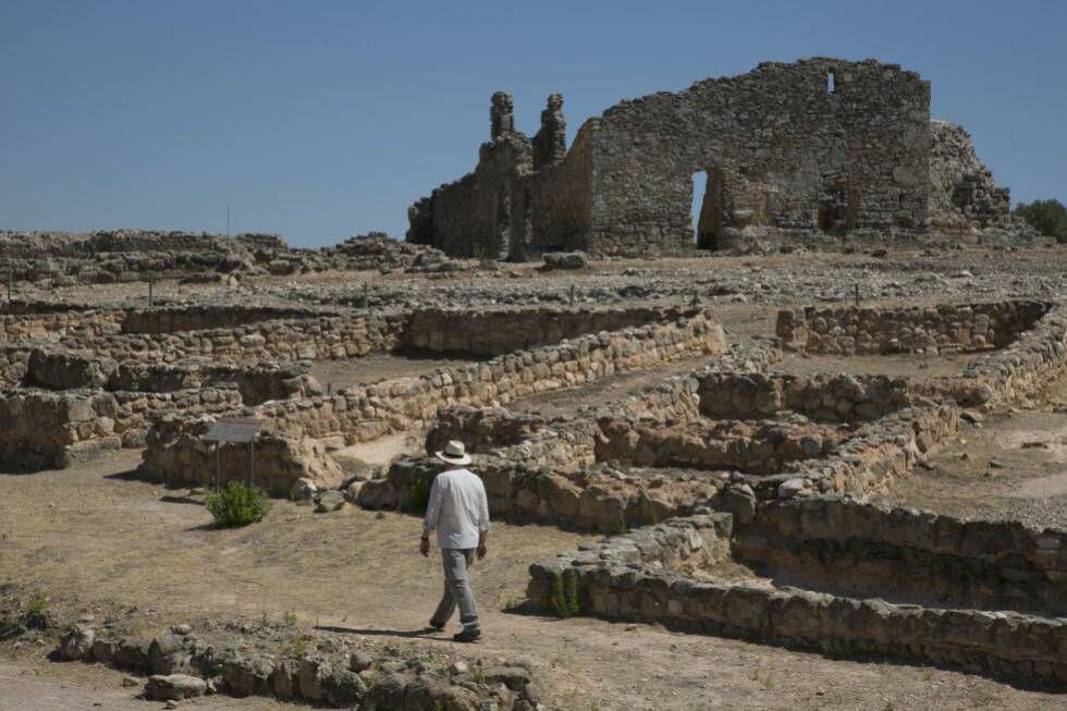 An archaeologist walks around the remains of shops and the homes of nobles.