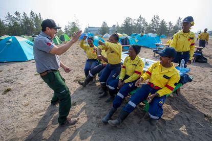 Frank McKay, left, a veteran wildfire fighter and liaison officer with the Northwest Territories Government Department of Environment and Climate Change, entertains South African firefighters with a Dene handgame at Yellowknife Airport in Yellowknife, Canada, Tuesday, Aug. 15, 2023. The city of Yellowknife, the territorial capital, declared a local state of emergency Monday night, citing an imminent wildfire threat. (Bill Braden/The Canadian Press via AP)