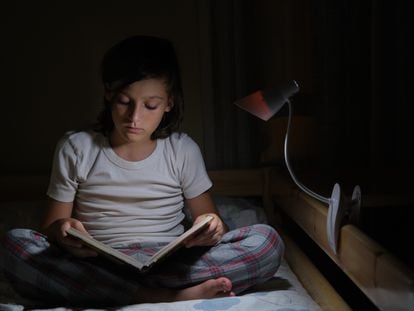Boy reading in bed with reading lamp