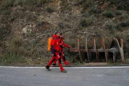 Mountain rescue firefighters walk past a drill bit after leaving the area.