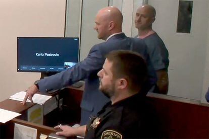 Joseph David Emerson, 44, is shown in the background at his first appearance before judicial authorities.