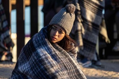 Colombian migrant Gisele, 18, bundles up against the cold after spending the night camped alongside the US-Mexico border fence on December 22, 2022 in El Paso, Texas. 