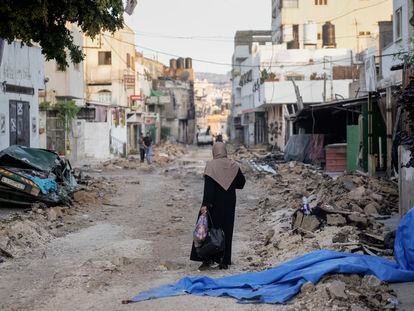 A Palestinian woman walks on a damaged road in the Jenin refugee camp in the West Bank, Wednesday, July 5, 2023, after the Israeli army withdrew its forces from the militant stronghold.