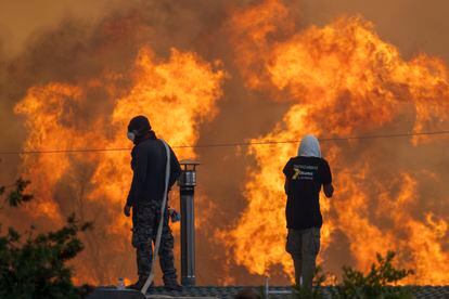 Residents stand on their roofs in front of huge flames at the village of Gennadi