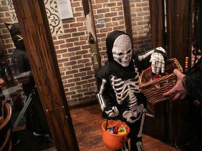 A child goes trick-or-treat at a restaurant on Halloween, in New York City, 2019.