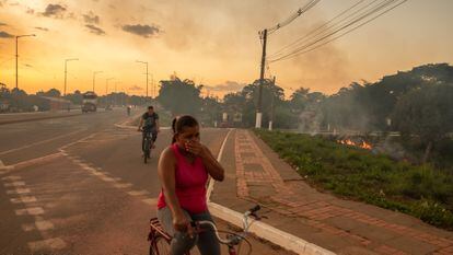  A woman covers her mouth and nose during a forest fire in Rio Branco, Brazil, in July of 2022.