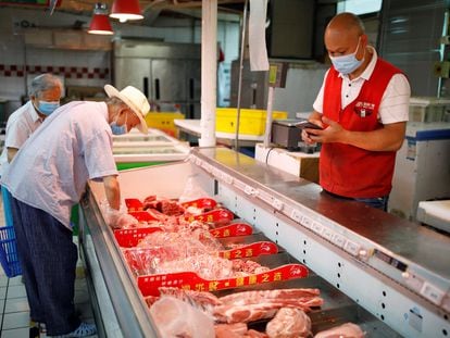 Elderly people shop at the meat section inside a supermarket in Beijing.