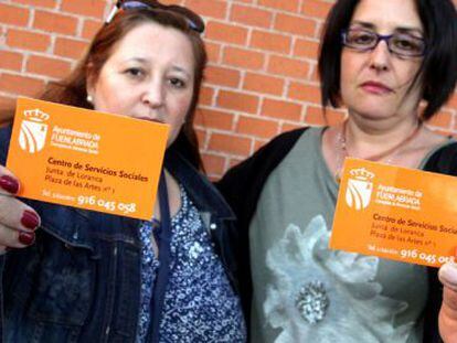 Two residents of Fuenlabrada hold up the social services card that is offered to undocumented migrants in their city.