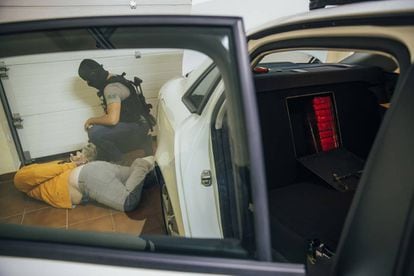 A police officer arrests a member of a drug ring found stashing packages of cocaine into a hiding place in the back seat of a car in Pontevedra.