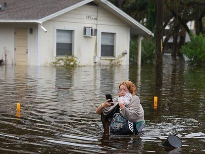 A resident wades through floodwaters after having to evacuate her home during Hurricane Idalia on August 30, 2023, in Tarpon Springs, Florida.