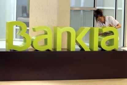 An employee cleans the Bankia logo.
