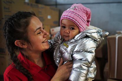 Ina holds her daughter Vladislava in her arms at the transit center where she is sheltering with her husband and son.