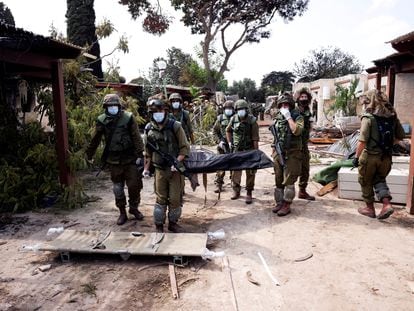 Israeli soldiers carry the body of a victim of an attack by militants from Gaza at Kibbutz Kfar Aza, in southern Israel.